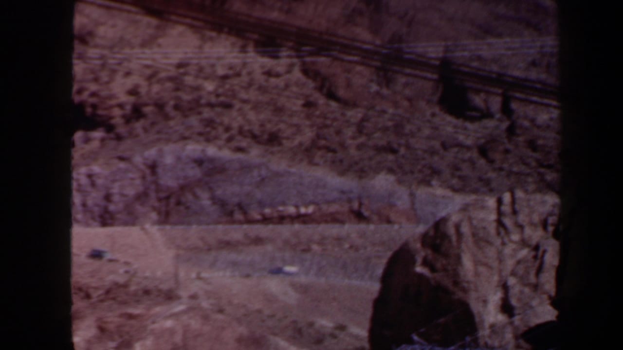 Rocky arid hillside with a dirt road and overhead cables.