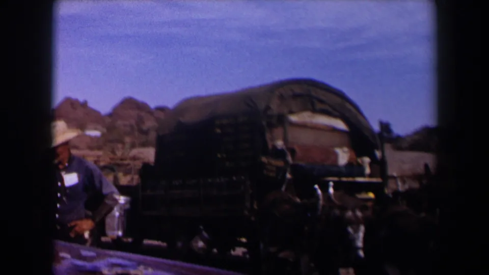 1958 Texas frame showing a cowboy-hatted adult beside the covered wagon while the donkey team remains in front.