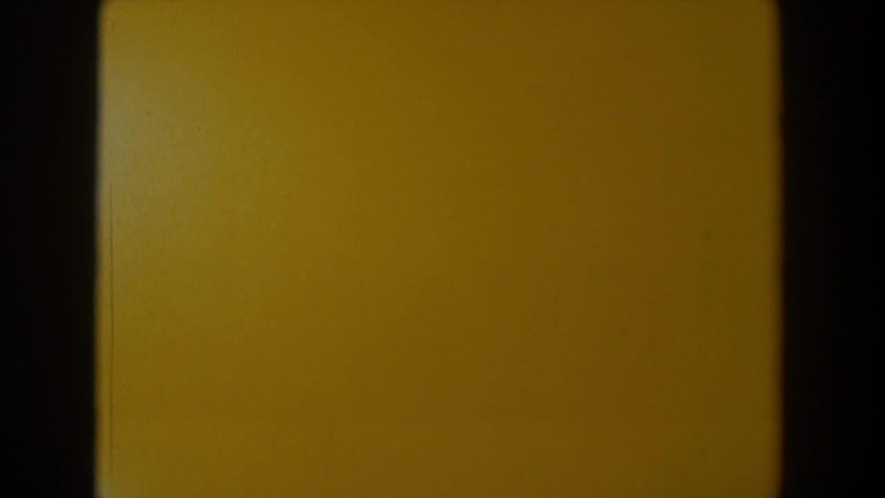 1958 Texas 8mm frame showing a mostly yellow blank field bordered by dark film edges, with dust and uneven exposure.