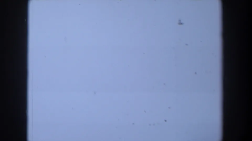 1958 Texas 8mm frame with a pale blue-white blank field, dark side borders, dust marks, and slight color unevenness.