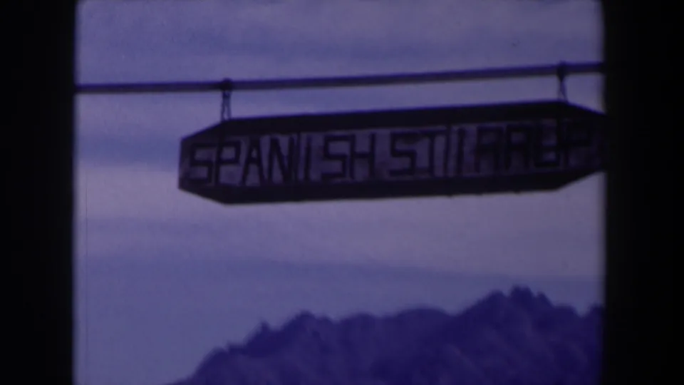 1958 Texas 8mm frame with the Spanish Stairs sign above a distant rugged mountain range.