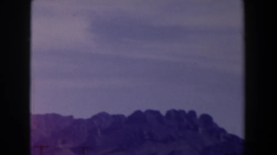 1958 Texas 8mm frame showing a distant mountain ridge under a pale purple sky after the sign has moved out of view.