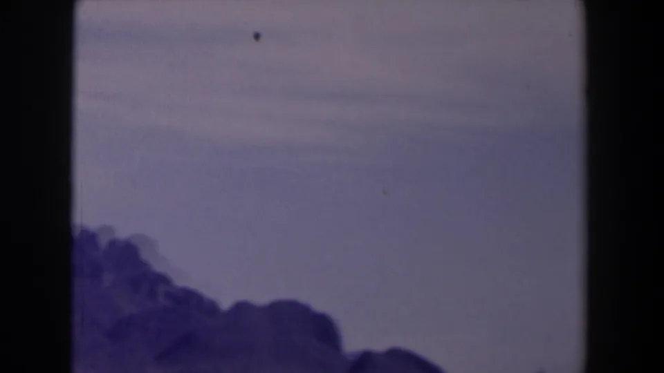 1958 Texas 8mm view of a rugged horizon and broad hazy sky, with soft focus and dark vertical gate edges.