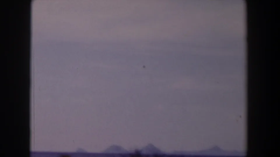 1958 Texas 8mm frame showing a broad washed sky, low open terrain, and small distant hills near the horizon.