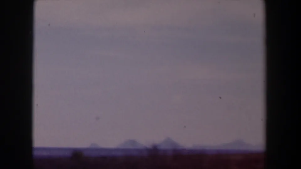 1958 Texas 8mm view of a dim open horizon, faint hills, and hazy sky, with visible gate edges and aged film color.