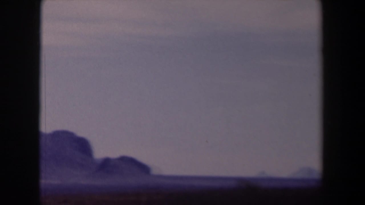 Distant mountain ridge under a hazy blue sky, partly obscured by dark frame edges.