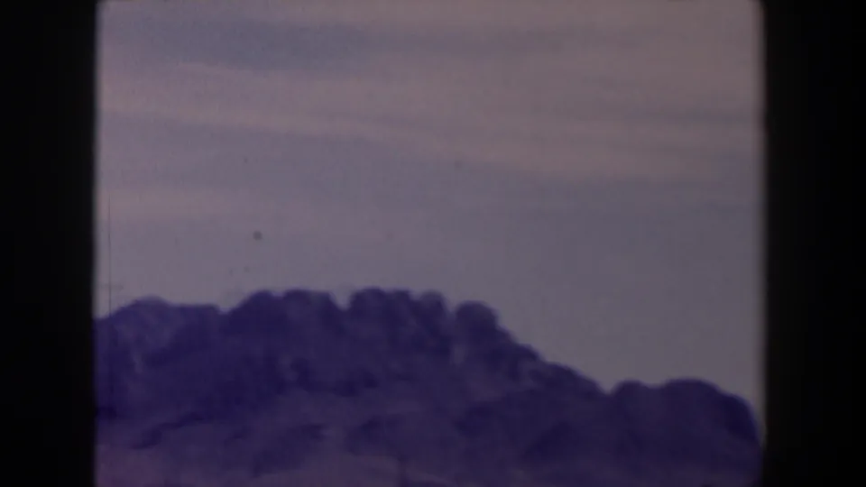 1958 Texas 8mm view of a rugged purple mountain ridge seen through dark vertical and horizontal framing.
