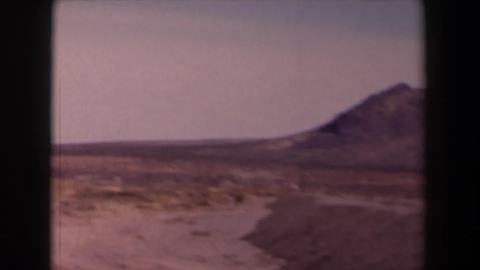 1958 Texas 8mm frame of a broad dry plain, distant ridge, and mountain slope at the edge of the frame.