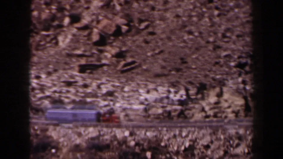 The red truck and white trailer continue across the Texas desert highway, framed by dark 8mm contact edges.