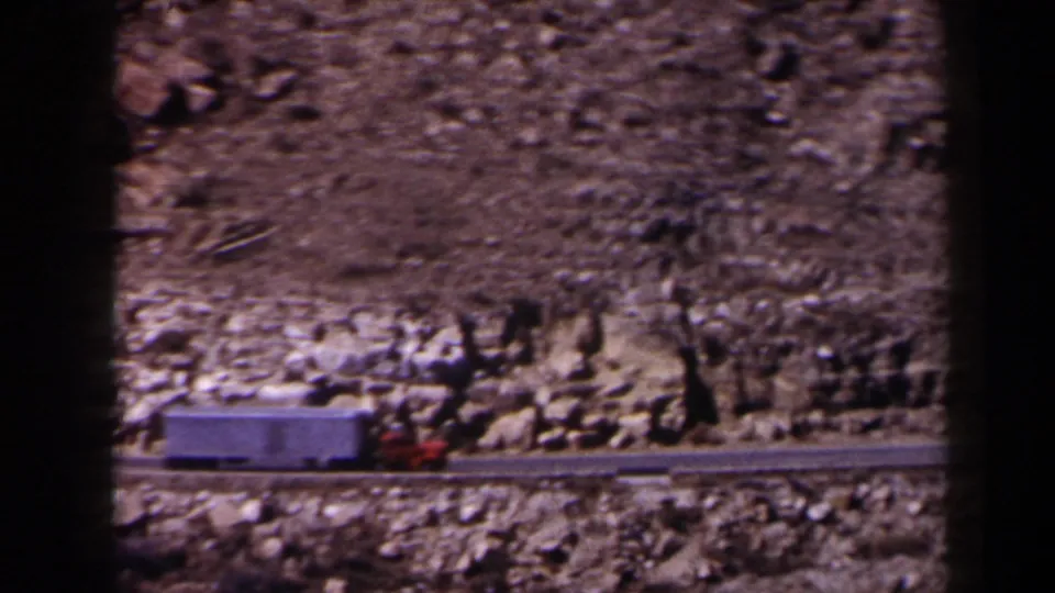 The truck nears the right side of the 8mm frame as it travels along the Texas mountain highway in faded color.