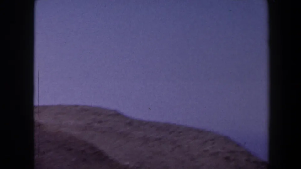 1958 Texas 8mm landscape frame showing a low brown ridge below pale blue sky, with soft exposure and dark film-edge framing.