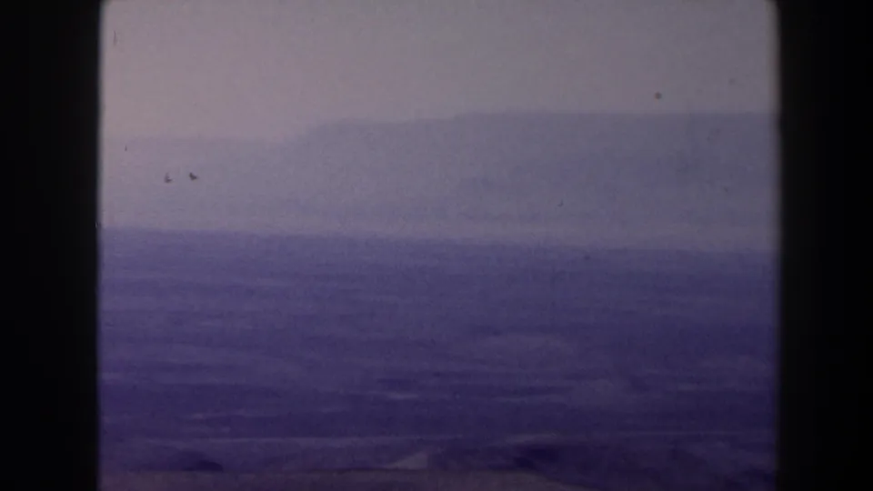 1958 Texas landscape frame showing layered hazy hills, open fields, and a pale overcast sky in soft 8mm color.