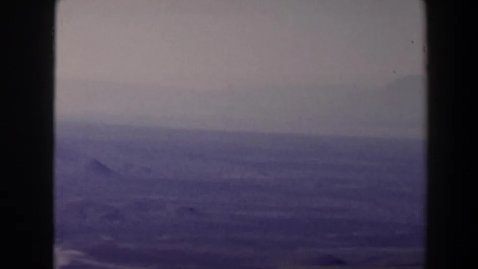 1958 Texas home-movie frame looking from high ground toward faint ridges and a broad arid landscape.