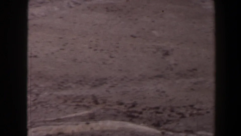 1958 Texas 8mm view of dry rocky foreground, pale slopes, and distant rolling land beneath a hazy horizon.