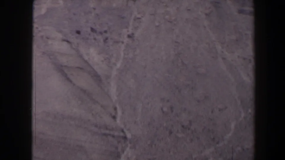 1958 Texas home-movie frame of a gray rock face, with branching cracks and soft 8mm color texture.