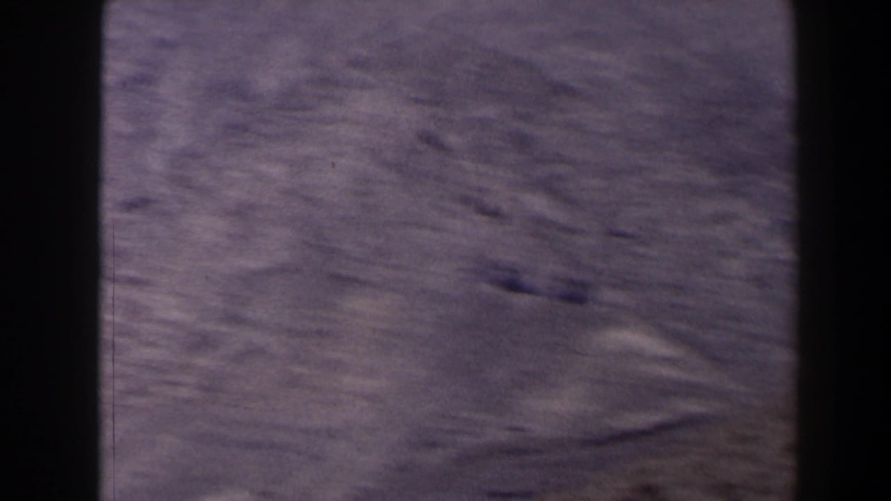 1958 Texas 8mm frame showing dry, brown ridges and sparse terrain from a high overlook, with visible film gate edges.