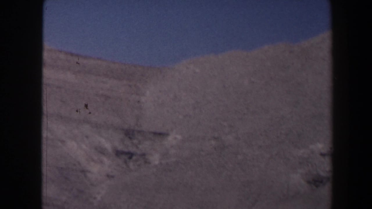 1958 Texas 8mm frame showing a pale rocky canyon slope or mountain face under clear sky, with heavy film border visible.