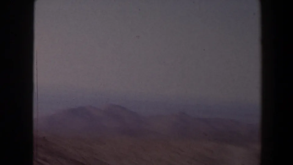 1958 Texas home-movie frame showing hazy desert hills, scrubland, and dark film gate borders.