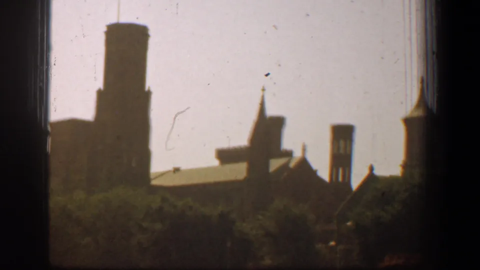 1961 Washington, DC 8mm view of silhouetted cathedral towers, spires, and rooflines framed by trees and dark film edges.