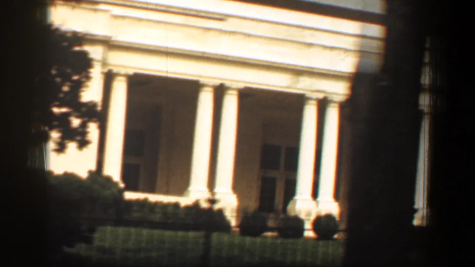 1961 Washington, DC frame showing a classical columned memorial facade, likely the Lincoln Memorial, partly obscured by trees.