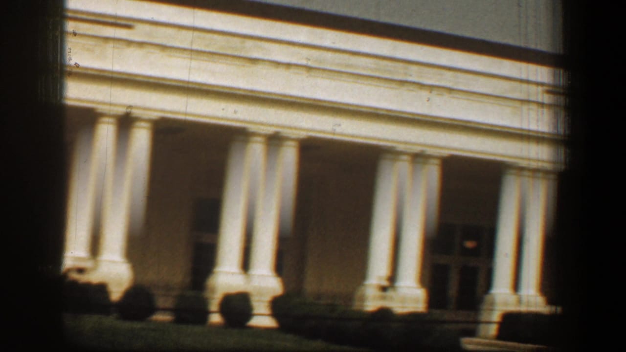 1961 8mm view of the White House facade in Washington, DC, with white columns, portico shadow, and dark frame edges.