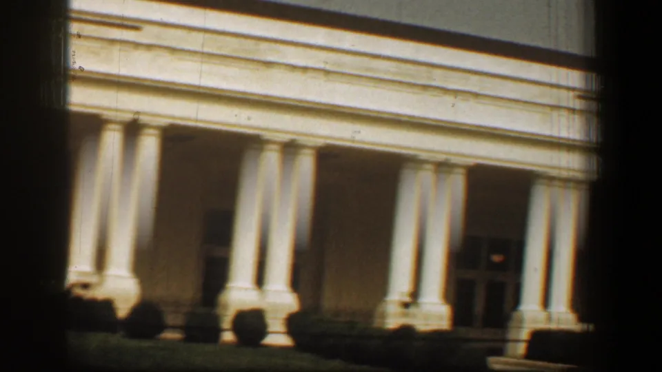 1961 8mm view of the White House facade in Washington, DC, with white columns, portico shadow, and dark frame edges.
