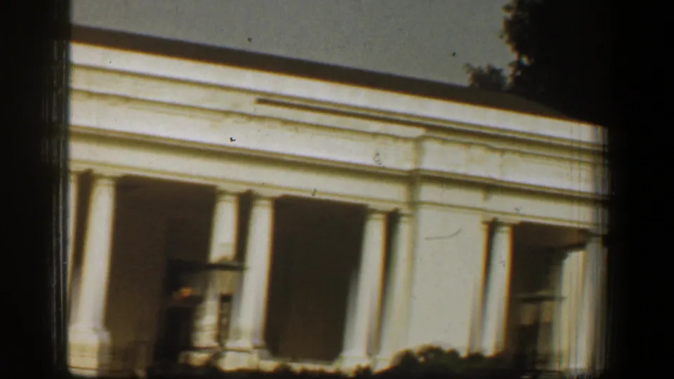 White House exterior in Washington, DC, showing the portico, white columns, recessed doorway, and sunlit roofline on 8mm film.