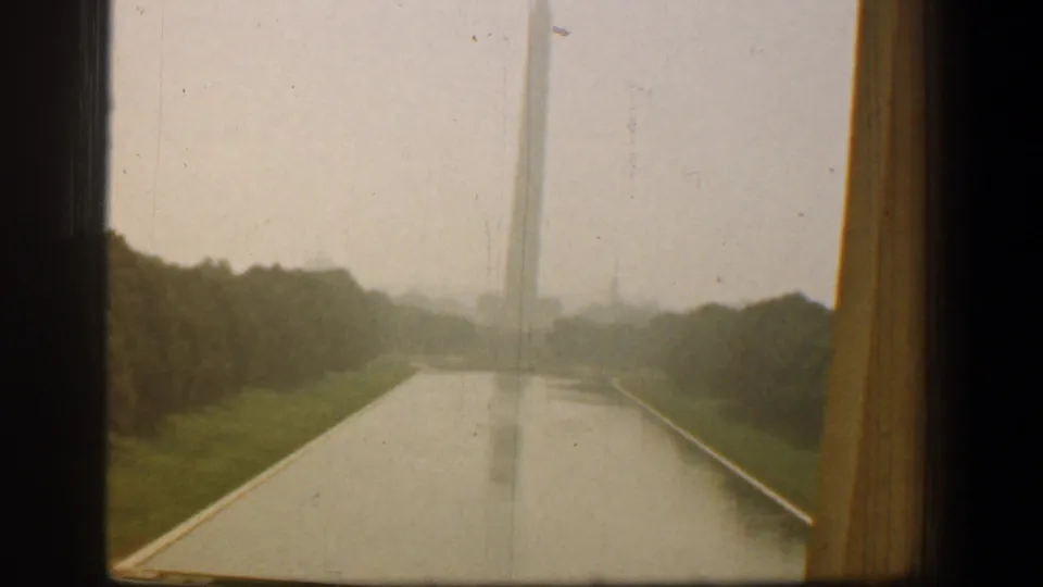 1961 Washington, DC frame with the Washington Monument shifted left of center, the Reflecting Pool below, and trees along the water.