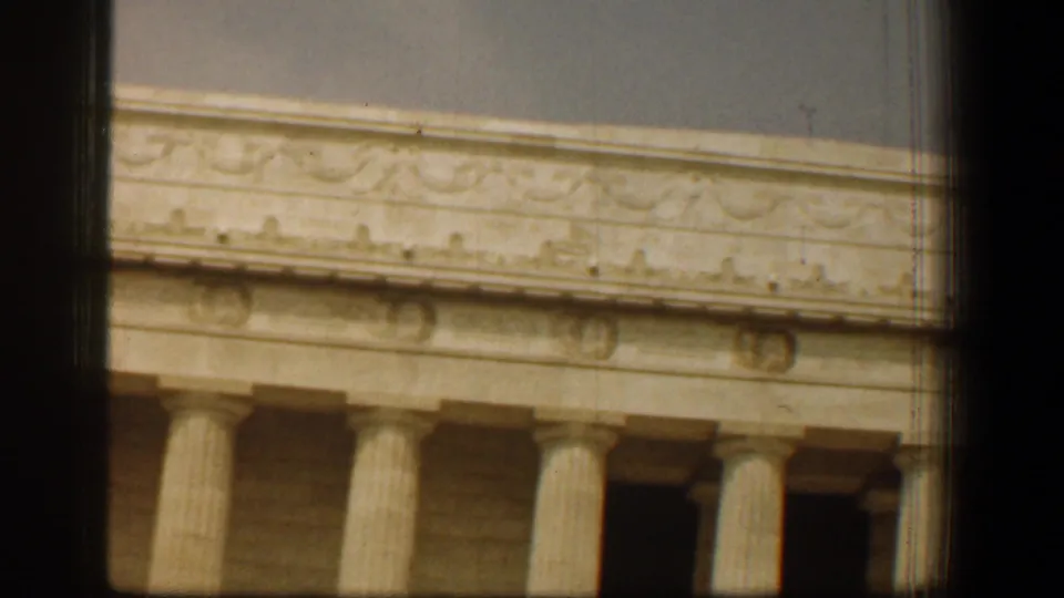 Close 1961 8mm view of the Lincoln Memorial's columns, roofline, and carved facade under a hazy sky.