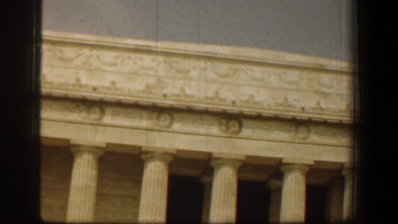 1961 8mm Washington DC view of the Lincoln Memorial facade, showing carved frieze detail and fluted columns in warm color.