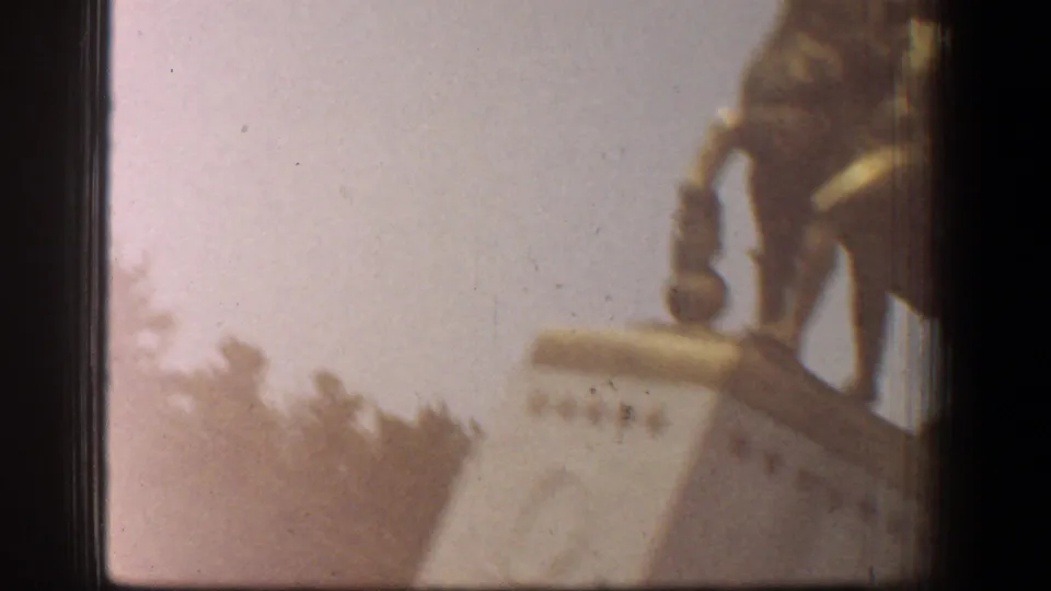 Soft 8mm close-up from the Washington, DC reel showing a worn structural edge and thin wire, with trees faintly visible below.
