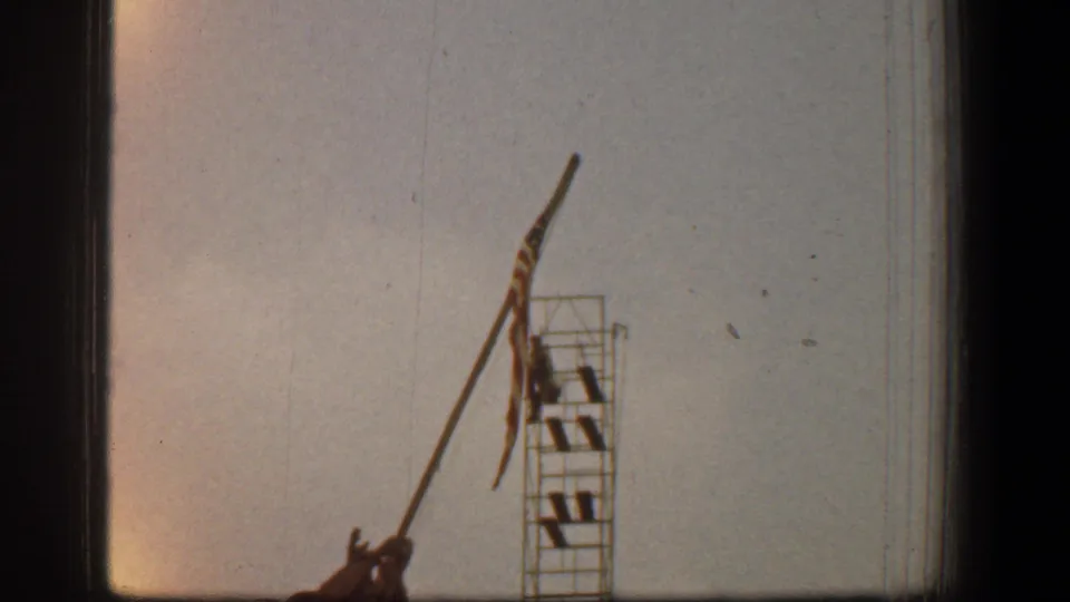 1961 Washington, D.C. 8mm frame showing the Marine Corps War Memorial partly cropped, with a raised flag and scaffolding beside it.