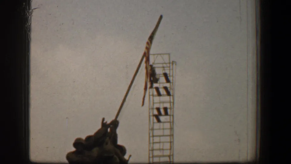 Low-angle 8mm view in Washington, D.C., showing the flag-raising sculpture cropped at the base, with scaffolding beside the memorial.