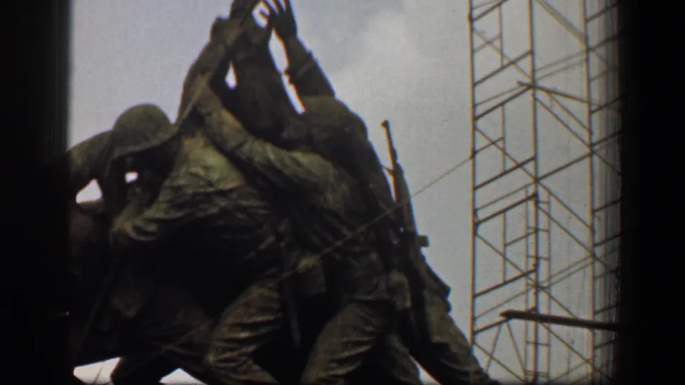 1961 Washington DC 8mm frame showing bronze Marine figures raising a flag, with metal scaffolding in the background.