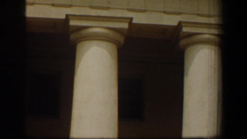 Close 1961 Washington, DC home-movie view of white classical columns against a shaded building facade.