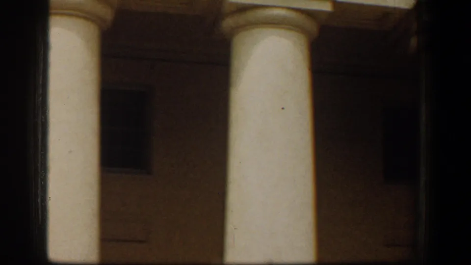 1961 Washington, DC footage showing two white classical columns and a dim facade behind them.