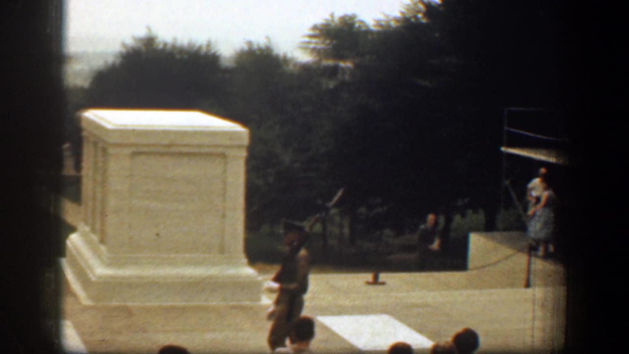 1961 Washington, DC home-movie view of a uniformed soldier carrying a rifle near a white marble memorial tomb.