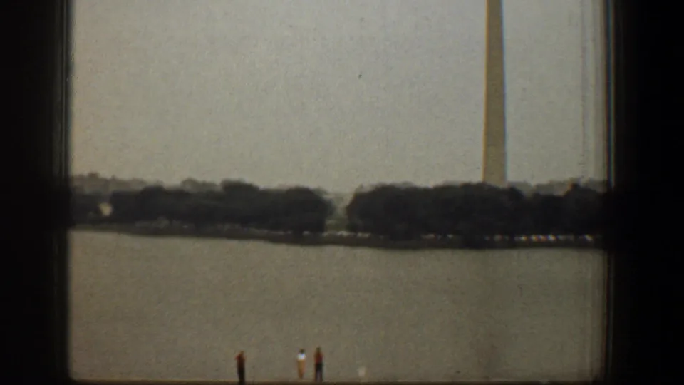 1961 Washington DC home-movie view of the Washington Monument across the Reflecting Pool, partly obscured by a dark window frame.