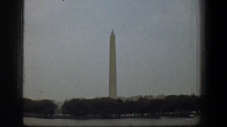 1961 Washington, DC home-movie view of the Washington Monument rising beyond trees near the water.