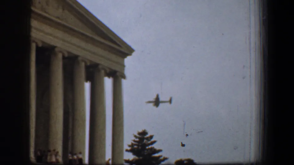 1961 Washington, DC home-movie frame showing the Supreme Court columns with a small airplane in the open sky.