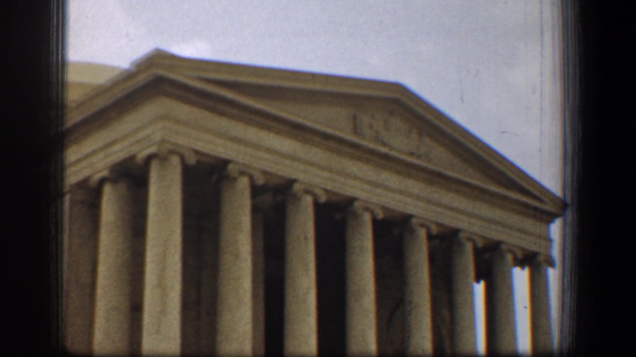 1961 Washington, DC home-movie frame showing the Jefferson Memorial columns, pediment, partial dome, and cloudy sky.