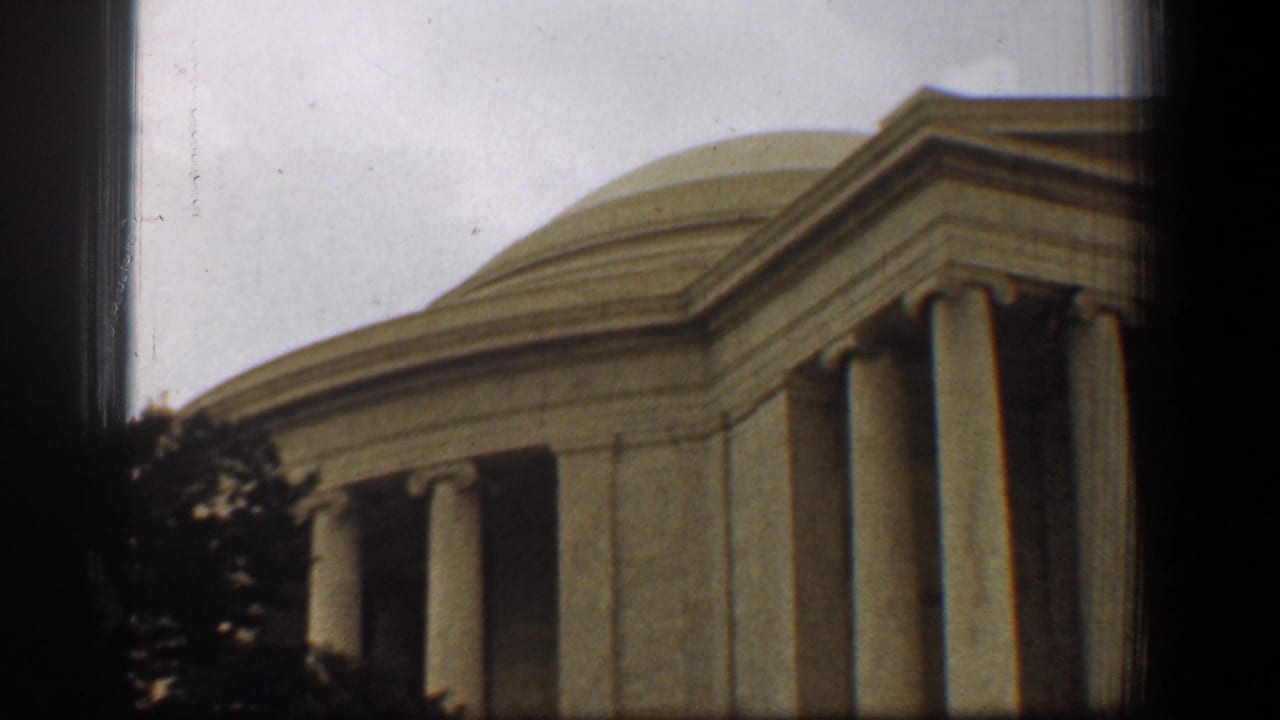 Jefferson Memorial columns and dome partly obscured by dark vertical borders and trees.