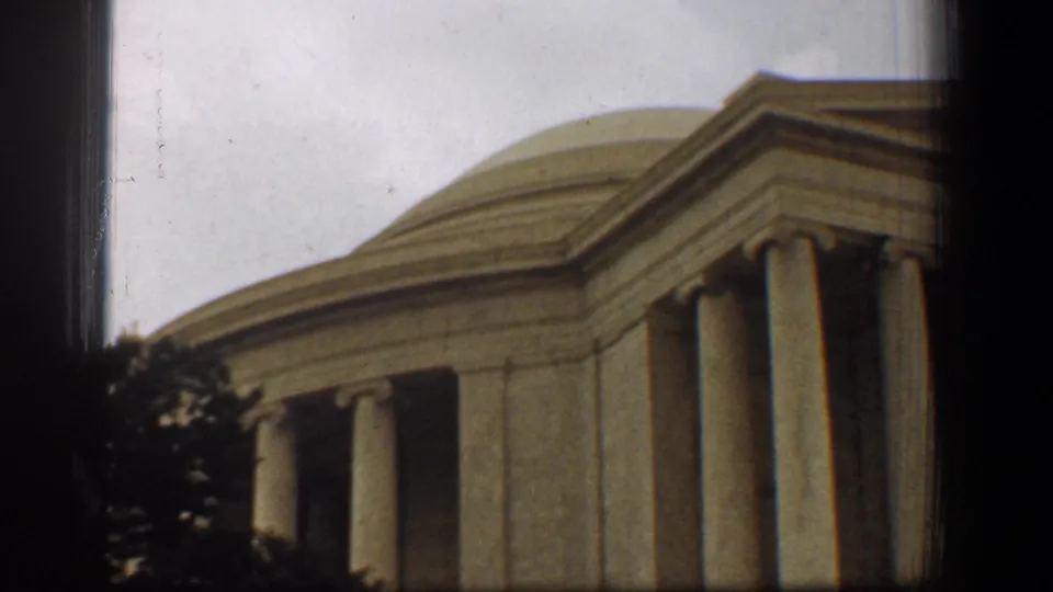 1961 8mm view of the Jefferson Memorial in Washington, DC, with columns, dome, trees, and dark frame borders.