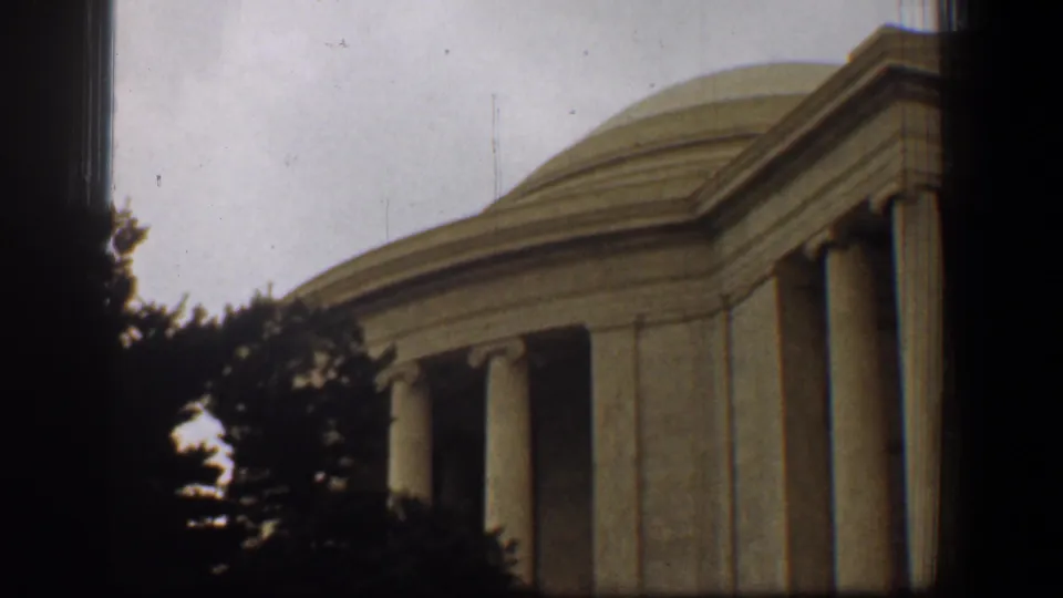 1961 Washington, DC home-movie frame showing the Jefferson Memorial dome, columns, trees, and heavy dark borders.