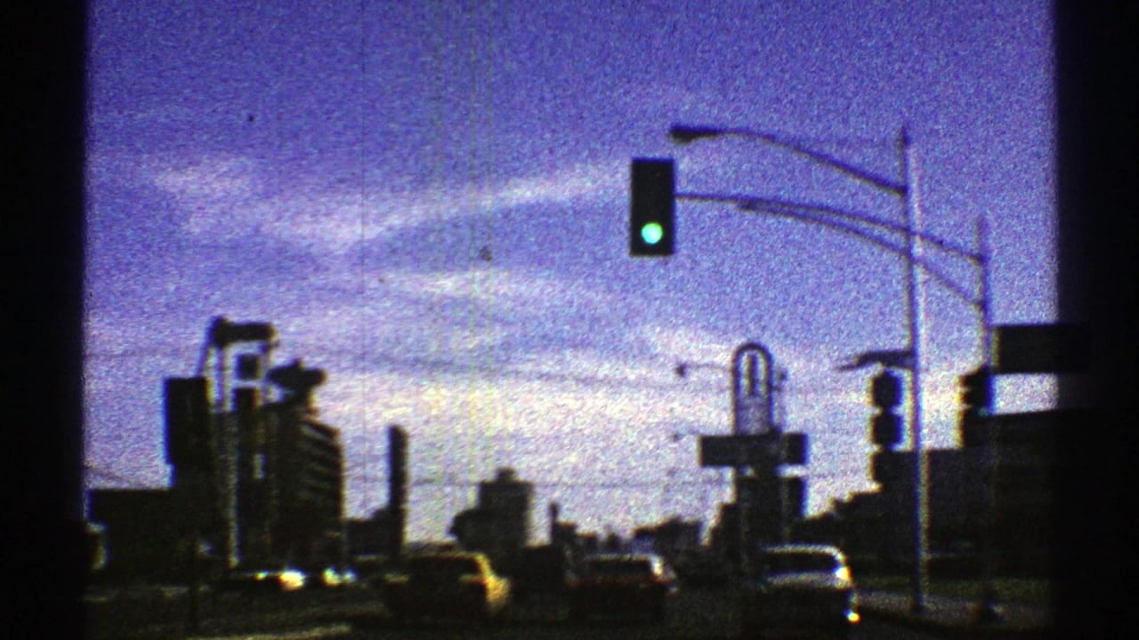 1969 Nevada street view from a moving vehicle, with a green signal, mid-century cars, commercial buildings, and roadside signs.