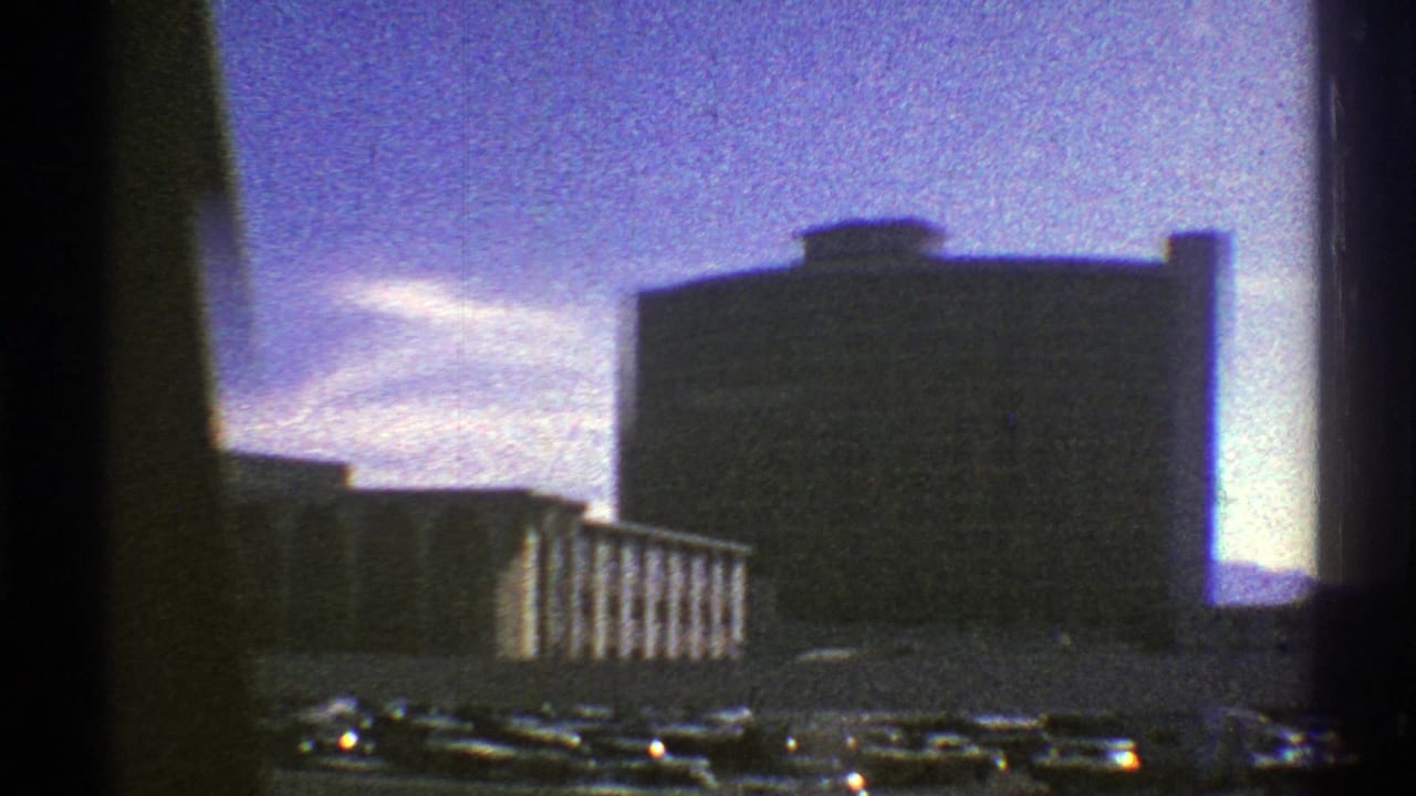 Roadside building seen through a moving car window under a purple sky.
