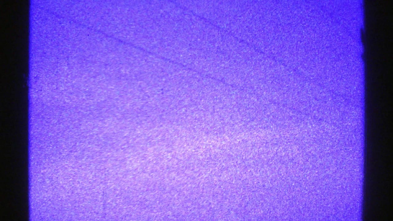 The clip ends on a purple-toned 8mm texture frame with grain, scratches, and minimal visible scenery.