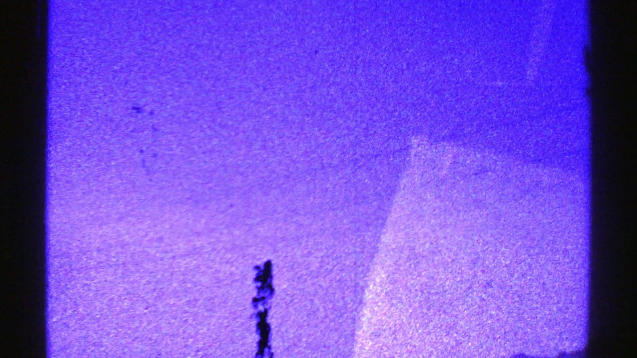 Nevada 1969 8mm frame with blue-tinted mountains, open sky, dark film edge, and a small bird-like shape overhead.