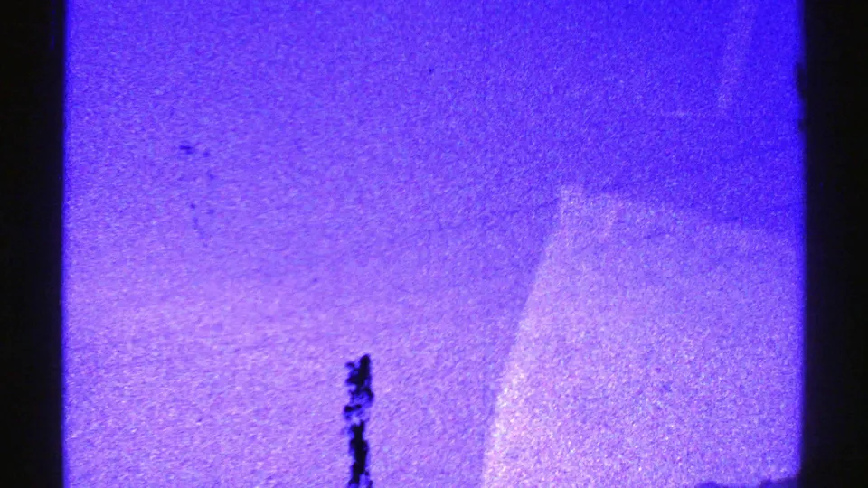 Nevada 1969 8mm frame with blue-tinted mountains, open sky, dark film edge, and a small bird-like shape overhead.