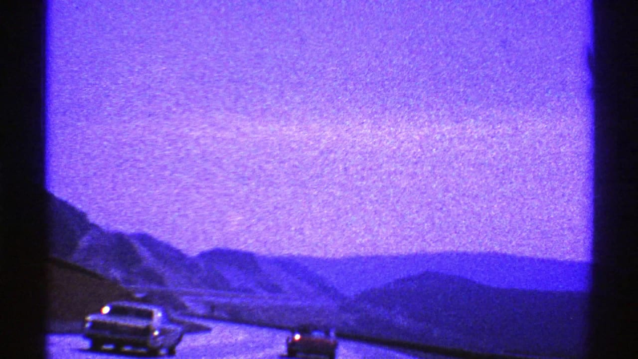 Cars on a mountain highway seen through a dark vehicle window frame.